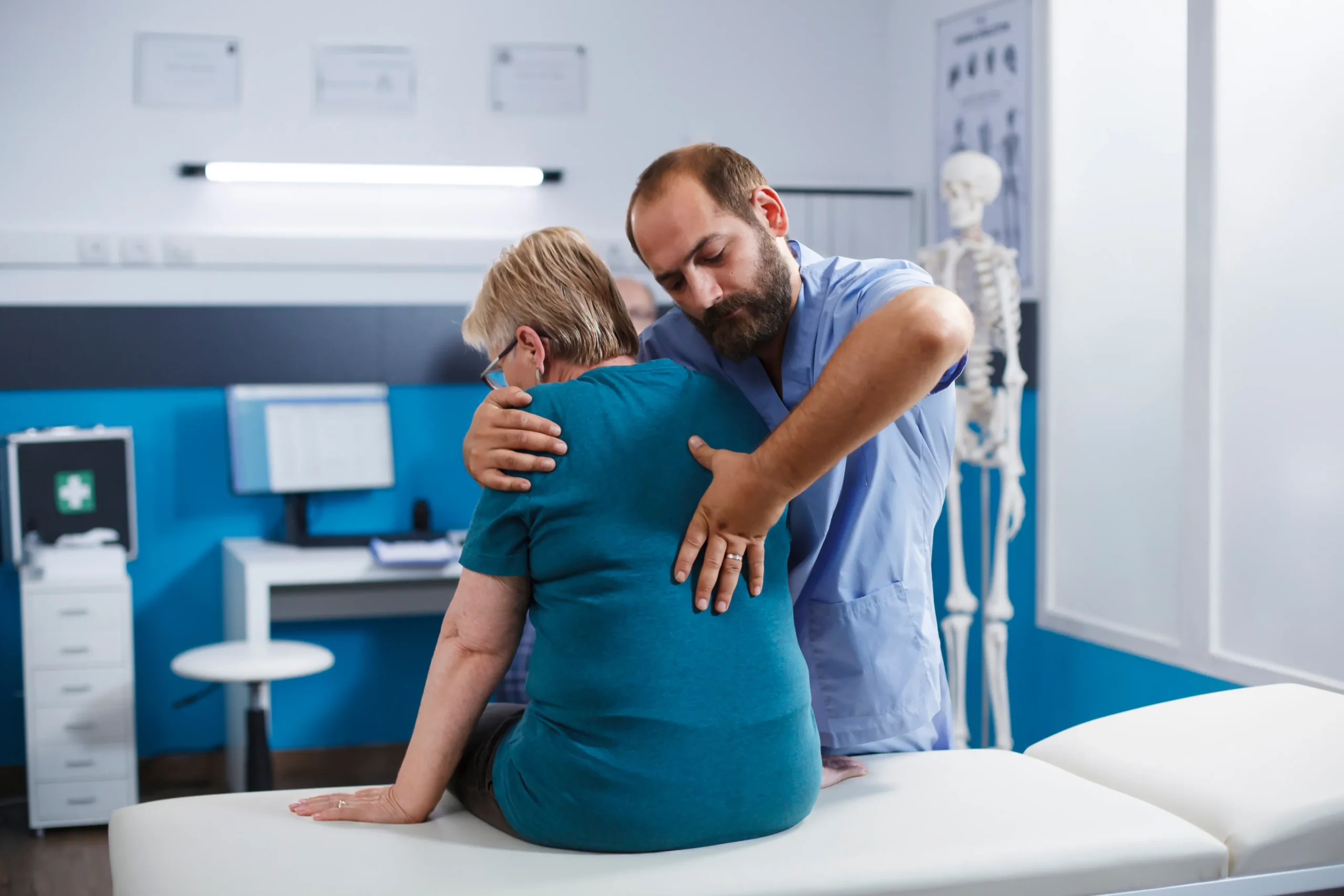 Orthopedic specialist examining an older patient for back pain and spinal mobility during an office visit.