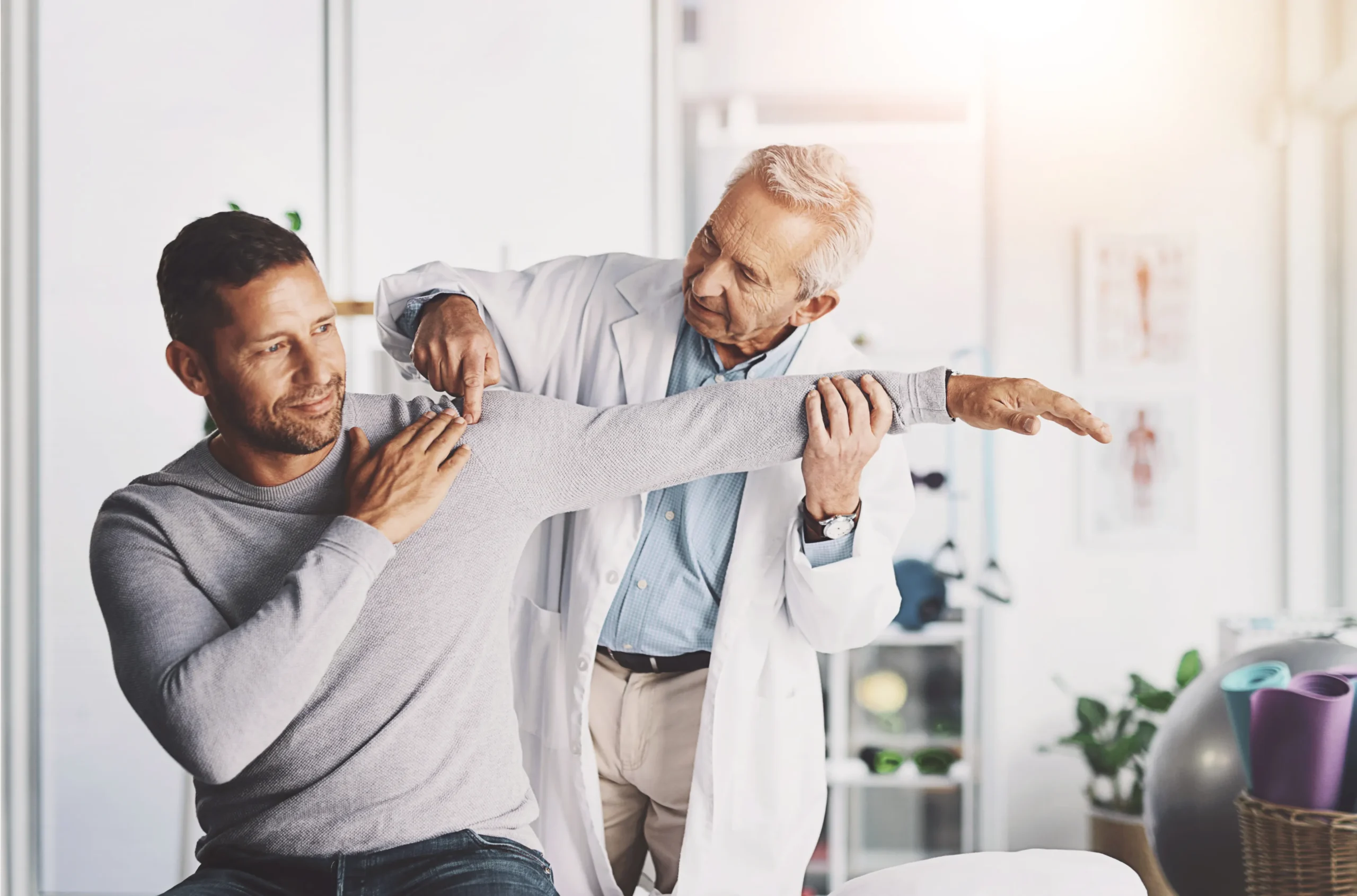 Orthopedic doctor evaluating a patient’s shoulder range of motion during a musculoskeletal examination.